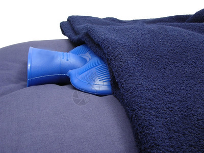 蓝色枕头上的毯子包裹在枕头上的热水袋图片