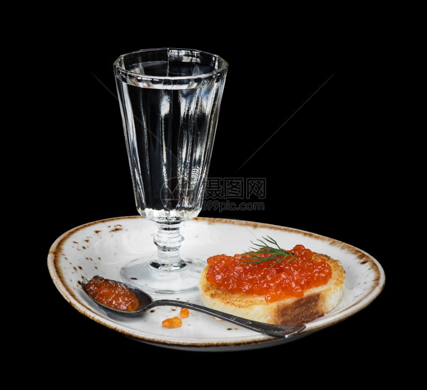 夹着红鱼子酱和伏特加杯放在一块用黑色隔着的瓷板上图片