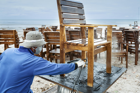 工人拿喷水枪在清洗修理木椅背景图片
