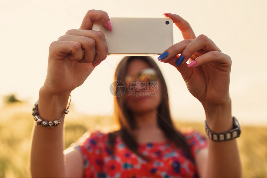 夏季户外使用手机智能穿着红裙子的年轻女特装图片