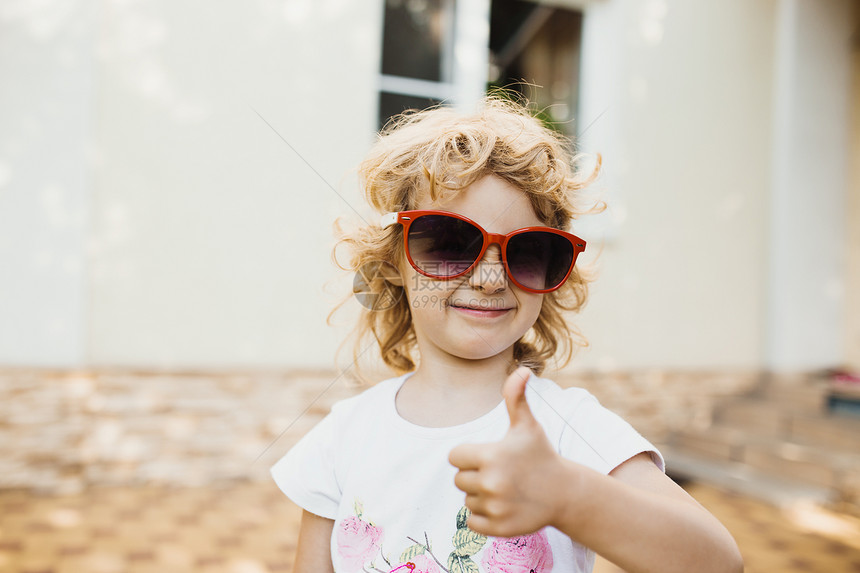 穿着红太阳眼镜的可爱小女孩举起拇指图片