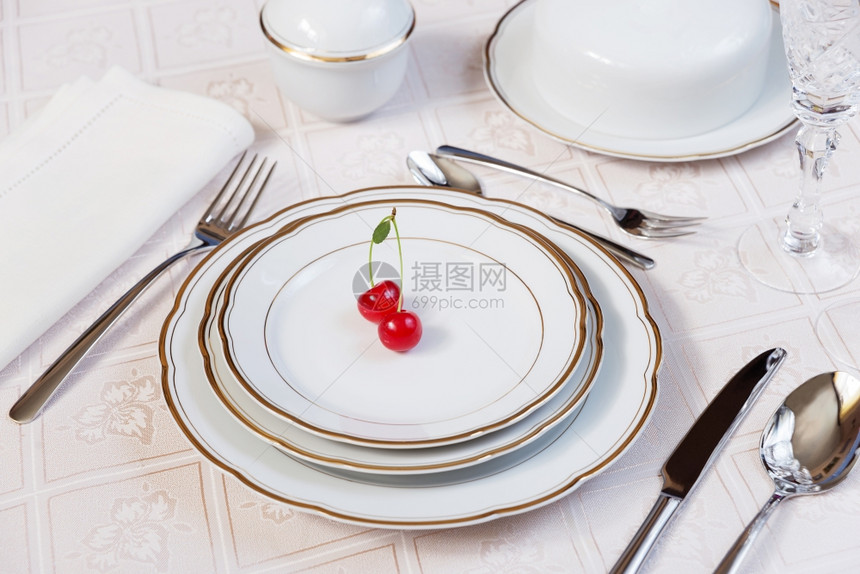 美的装饰桌上面有白色板晶杯水眼镜餐巾具和豪华桌布上的郁金花图片