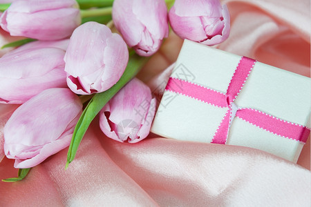 花束和礼品盒用粉红丝织物底的粉红色带捆绑图片