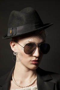 一个美丽的年轻模特肖像戴着黑帽子色背面戴墨镜的黑帽子图片