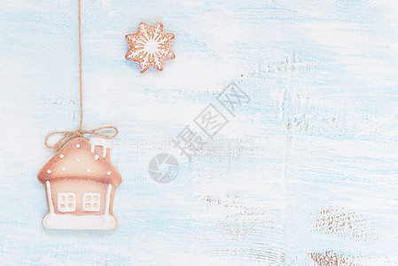 圣诞饼干作为房子和雪花在浅木背景上图片