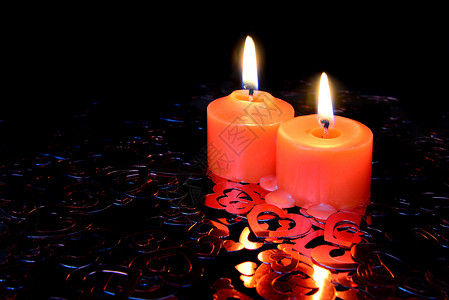 两根红蜡烛烧着在心形状的彩色面团黑暗背景上图片