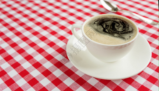 白瓷杯中浓黑咖啡红白彩布图片