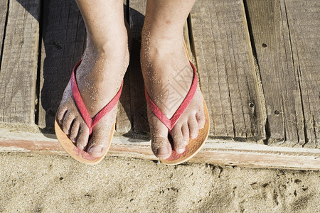 女人脚在海滩上粉红色丁字裤木板背景图片