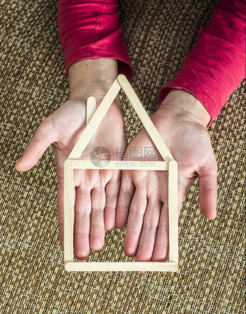 手拿着用木棍制成的模范房屋放在室内间图片