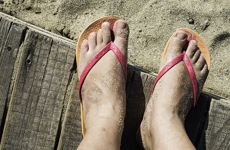 女人脚在海滩上粉红色丁字裤木板背景图片