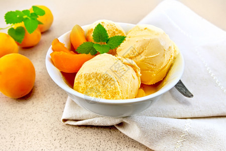 在碗中的冰淇淋白碗中的杏仁冰淇淋里面有水果片餐巾纸上的薄荷在背景花岗岩桌上背景