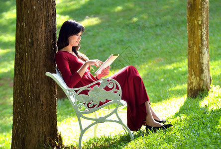 文艺的青年女子在公园里看书背景图片