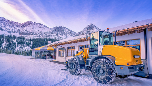 一辆装有防滑链的黄色铲雪车背景图片