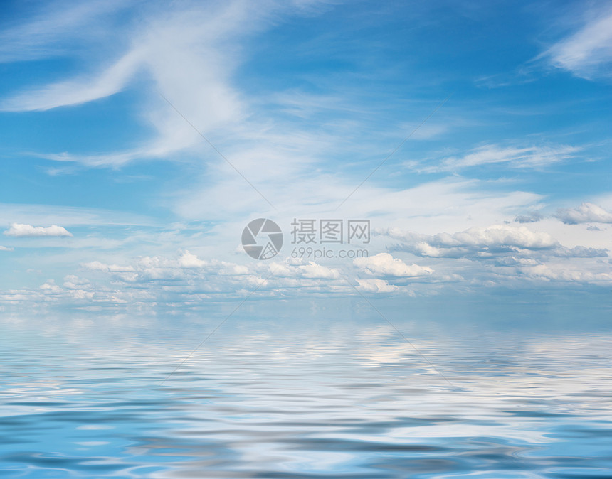 巨大的蓝色夏日天空全蓝有白卷毛积和圆云在小波浪的水面上反射图片