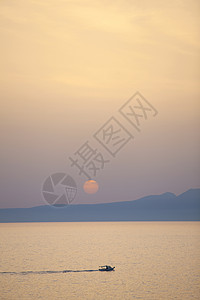 太阳下山时在Grekpons海岸附近域捕鱼的渔船高清图片