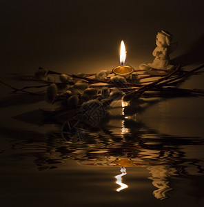 天使燃烧的蜡烛和柳树枝以小波浪反射在水面上图片