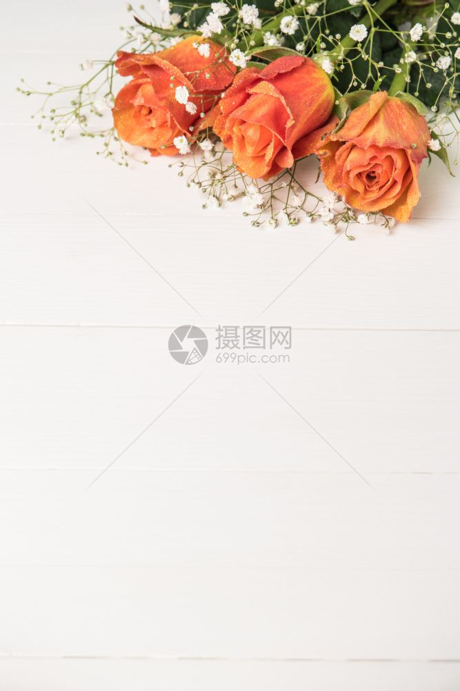 一束橙色玫瑰和木制桌上的吉卜赛人图片