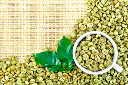 绿色咖啡豆和叶子黄粗织布的杯子图片