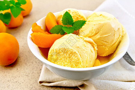 在碗中的冰淇淋白碗中的杏仁冰淇淋在花岗岩背景桌子上的餐巾加水果薄荷和勺子片背景