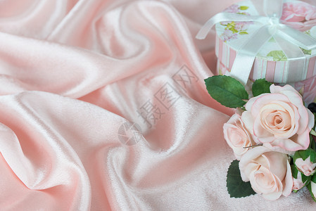 粉红玫瑰花束和礼物盒在卷粉丝织布背景上用弓头图片