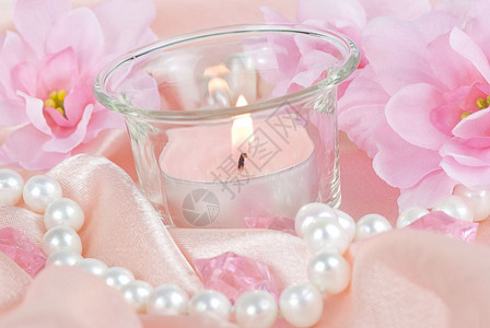 粉红花烧蜡烛和丝织上的珍珠项链背景图片