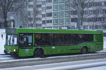 城市公共汽车行驶在被雪覆盖的马路上图片