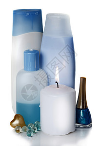 含有不同化妆品和燃烧的白蜡烛蓝色和玻璃瓶图片