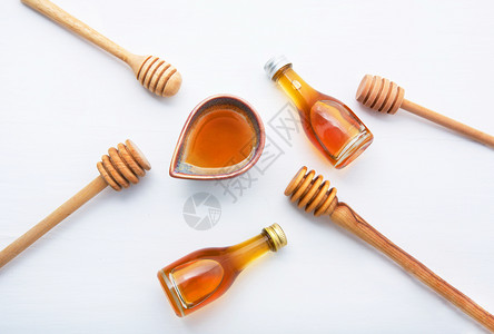 蜂蜜配有木制花瓶和小蜂白色木制背景图片