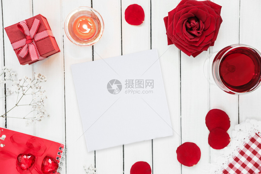 情人节假日配有酒杯红玫瑰礼盒弓和烧蜡烛的喜宴桌顶视图白纸卡上有复制空间图片