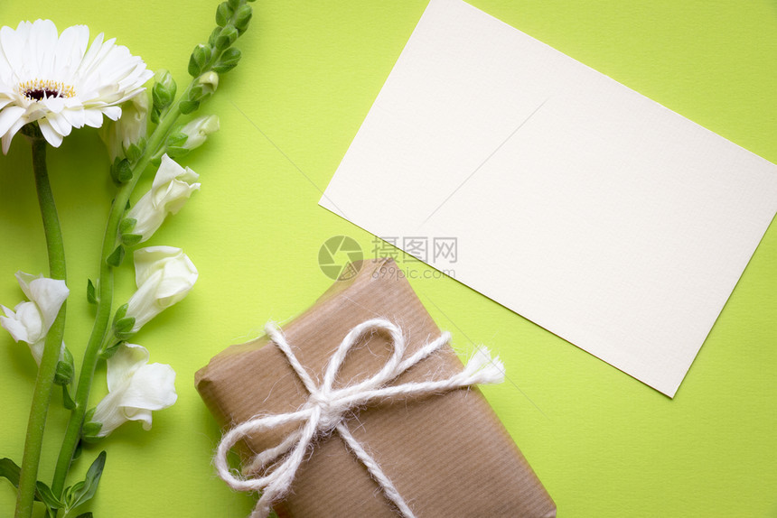 贴纸条的贺卡想法上面贴着白花和礼品盒包着棕色纸绑麻绳和弓并印在绿色背景上图片