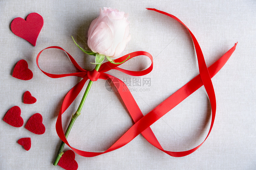 妇女白天用粉红玫瑰纸牌想法绑着丝带形状为8号周围有许多红心以古老的布料背景图片
