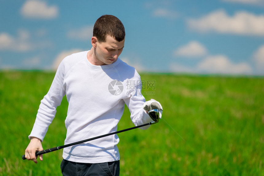 一个高尔夫球手在场上比赛前检查他高尔夫俱乐部的肖像图片