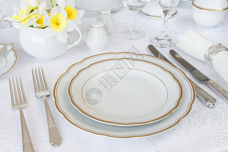 经典盛宴晚与豪华的瓷银器和白桌布上的春花图片
