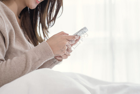 快乐的亚洲妇女早上在床使用智能手机女人高清图片素材