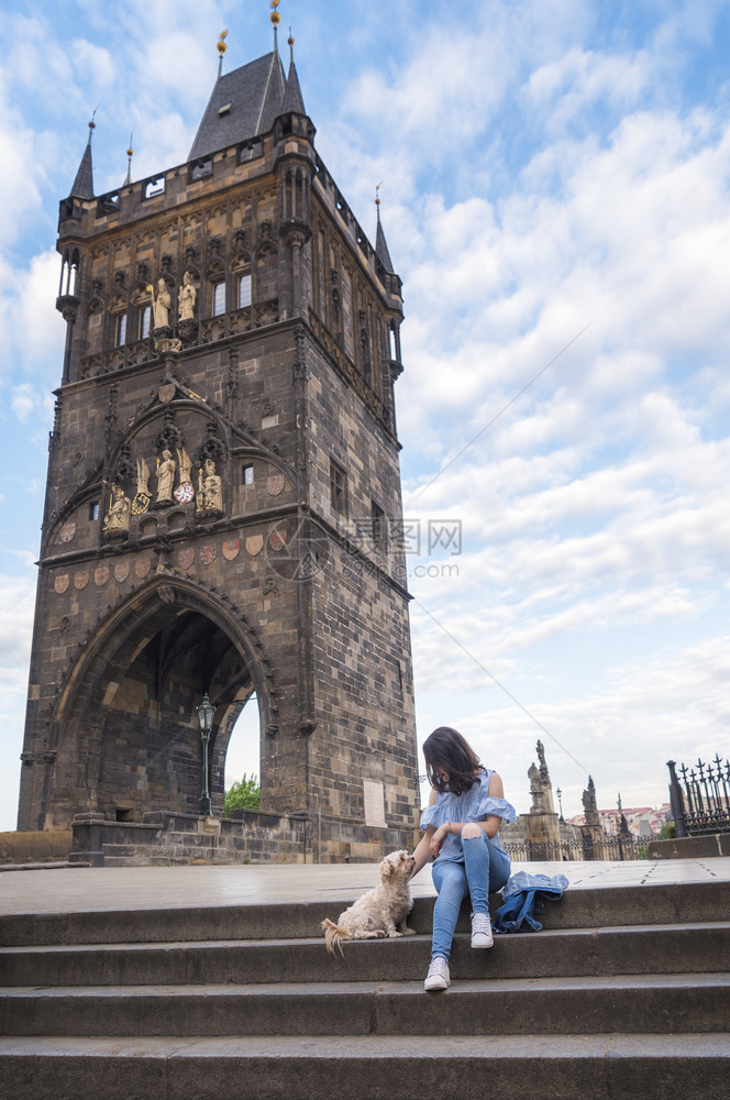 在czeh古城prague的chrls桥前的塔黑发女孩在楼梯上抚摸她的狗图片