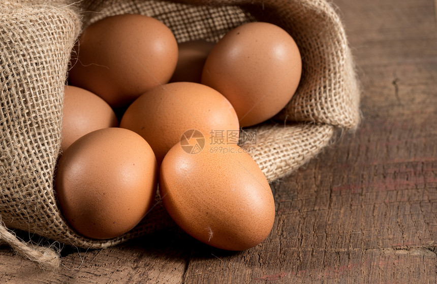 褐色有机鸡蛋的东方背景褐色有机鸡蛋安排在生锈木制桌子上的一个勃拉布袋内图片