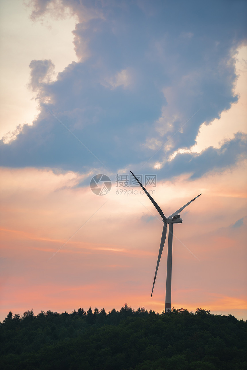 在一个木质山丘上的单一现代风车面对一个多彩的夏天日出蓝色时钟在badenwurtembg地区图片
