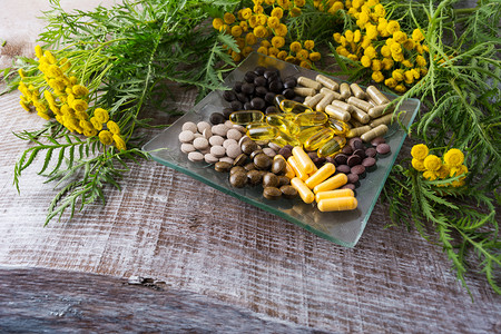 玻璃板上的Ayurvedic草药丸和刺青黄色开花植物生物学高清图片素材