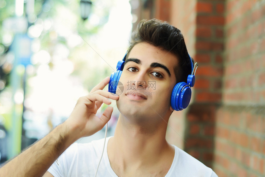 年轻人用蓝耳机在户外画像图片