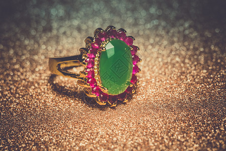 金色绿宝石戒指优雅的女首饰金环珍贵的绿宝石过滤背景背景