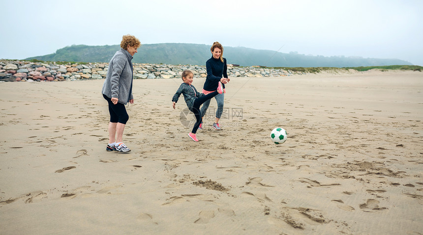 秋天在海滩上踢足球的三代女在海滩上踢足球的三代女图片