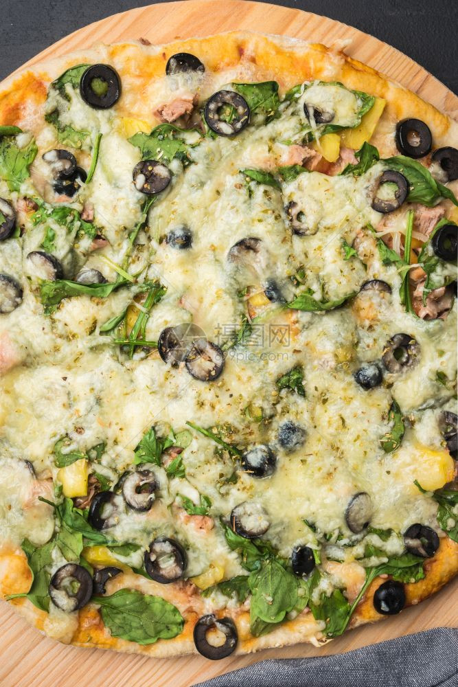 用菠菜西红柿黑橄榄和木本底烤锅上的奶油酪自制素食披萨图片