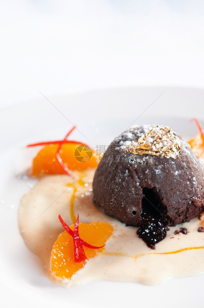 巧克力甜点巧克力味熔岩蛋糕香草酱柑橘白盘上的金叶子图片