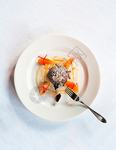 巧克力甜点巧克力味熔岩蛋糕香草酱柑橘白盘和叉子的金叶背景图片