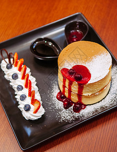 美味的樱桃奶酪蛋糕鲜草莓蓝和黑盘上奶油图片