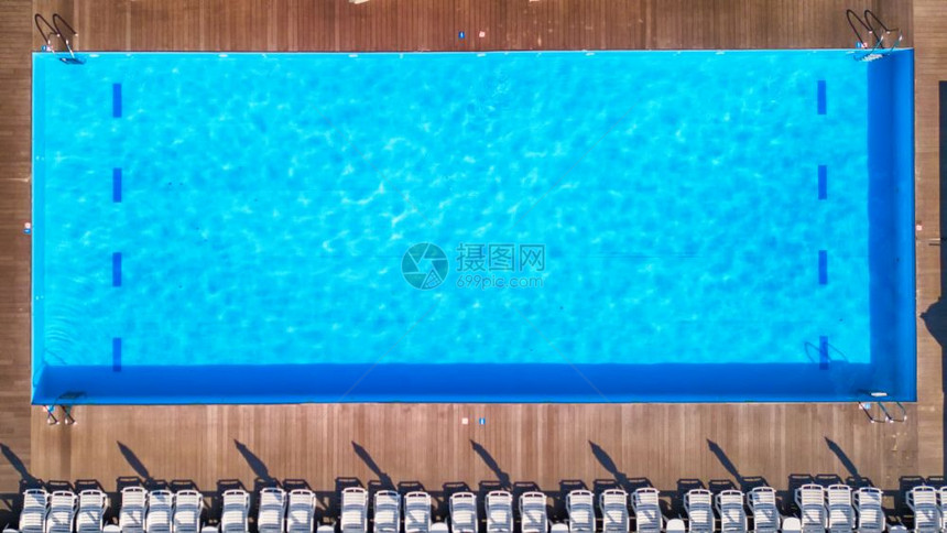 在私人游泳池附近的木制地板上看到防晒霜蓝色游泳池有清洁水蓝色游泳池暑假有白色的太阳床顶层风景图片
