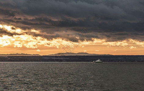 湖面的风景预示着日落时分黎明的阴云日落船在海浪中航行图片