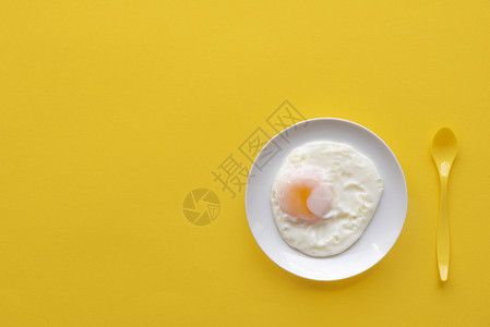 白盘上单煎蛋和黄勺子色背景背景图片