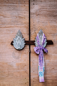 古老的旧木门有泰式莲花形状雕刻手柄和美丽的织物丝带背景图片