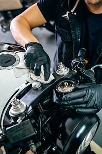 摩托车手套在他的车间里清洁一辆定制摩托车机械清洁一辆摩托车背景